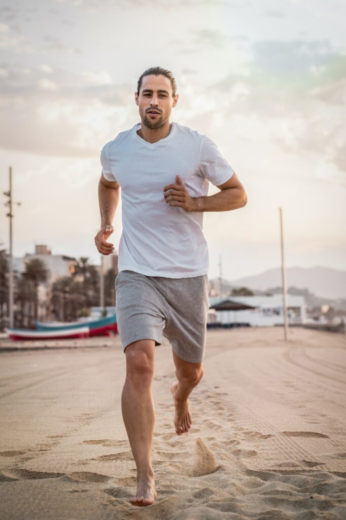 Athletic Caucasian male working out on the beach in the early morning - healthy lifestyle concept